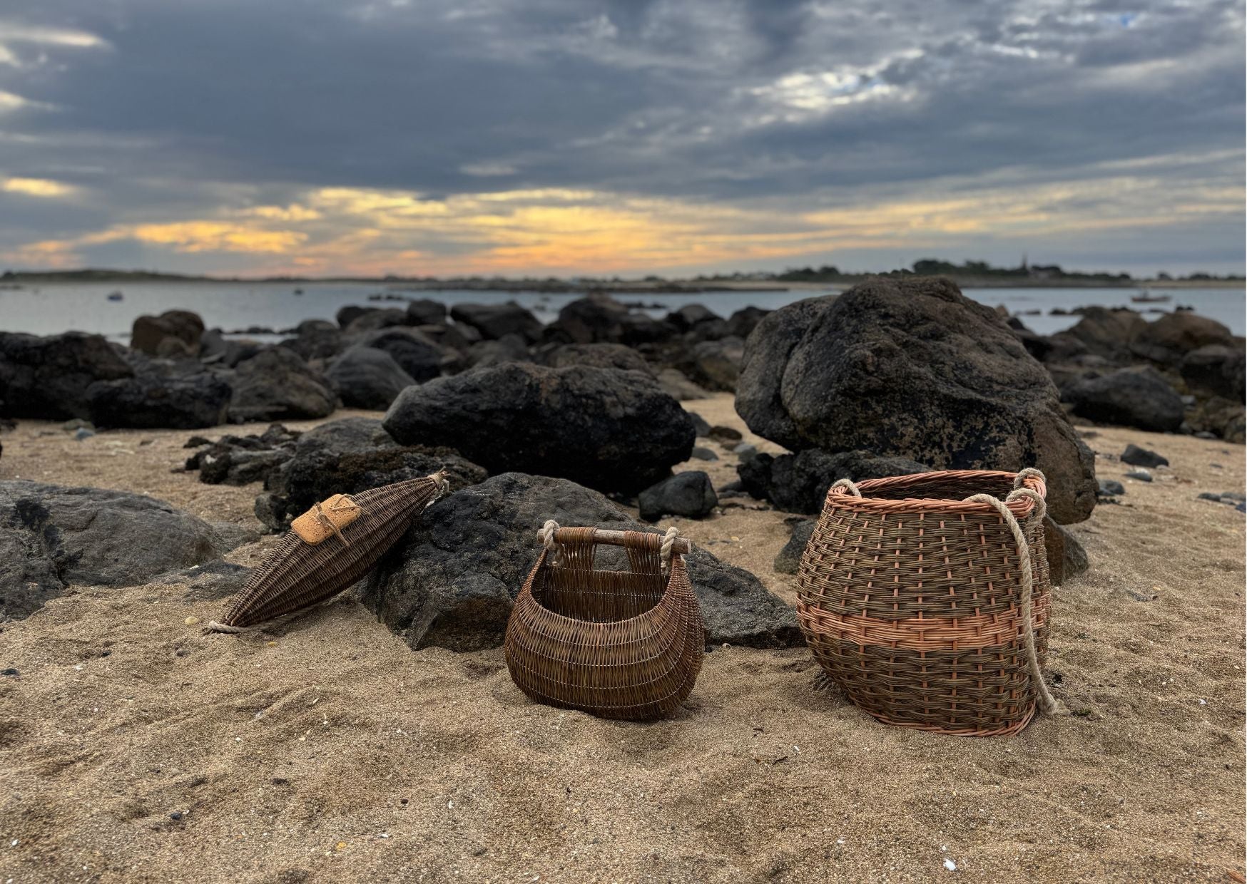 Claire Gaudion Guernsey willow fishing baskets on beach in Guernsey amongst rocks