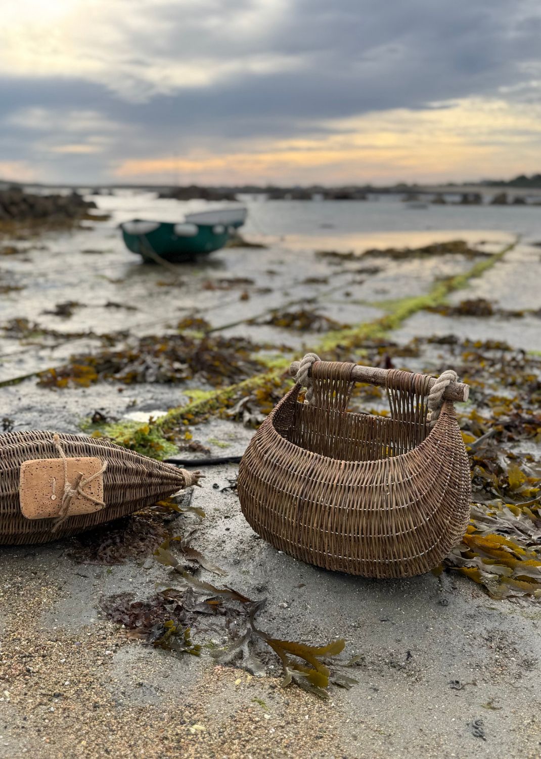 Woven baskets on a beach with water and boats in the background