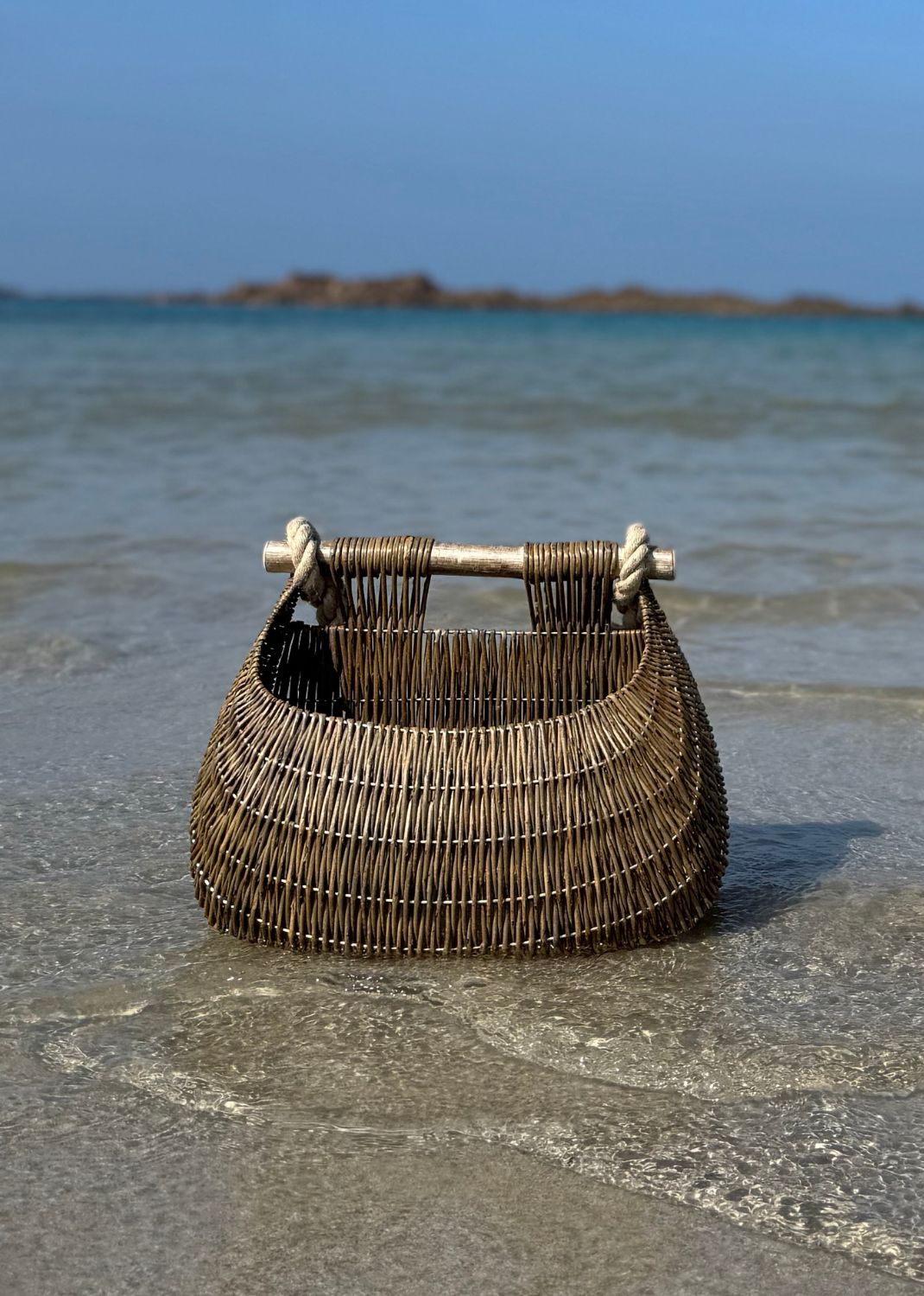 Willow basket on a sandy beach with ocean in the background