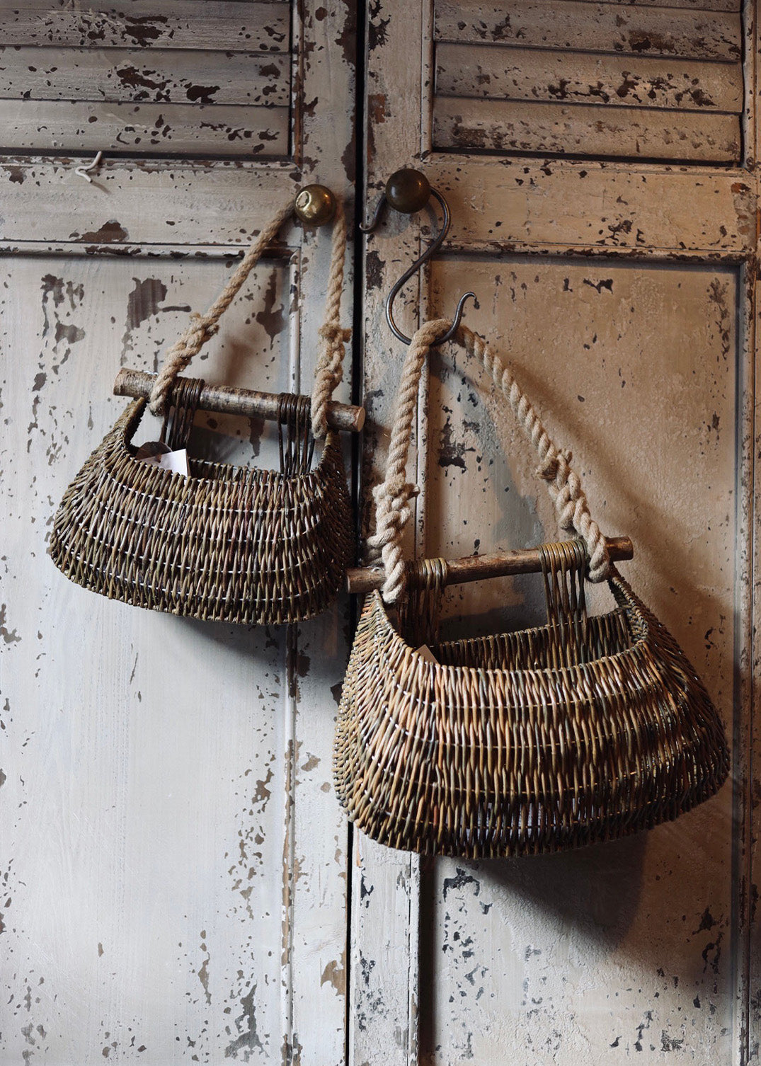 Guernsey willow baskets by Claire Gaudion hanging from rope strap on rustic door handle and iron hook