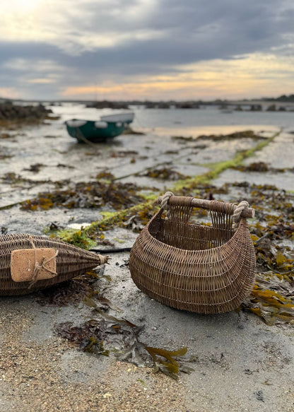 Woven baskets on a beach with water and boats in the background